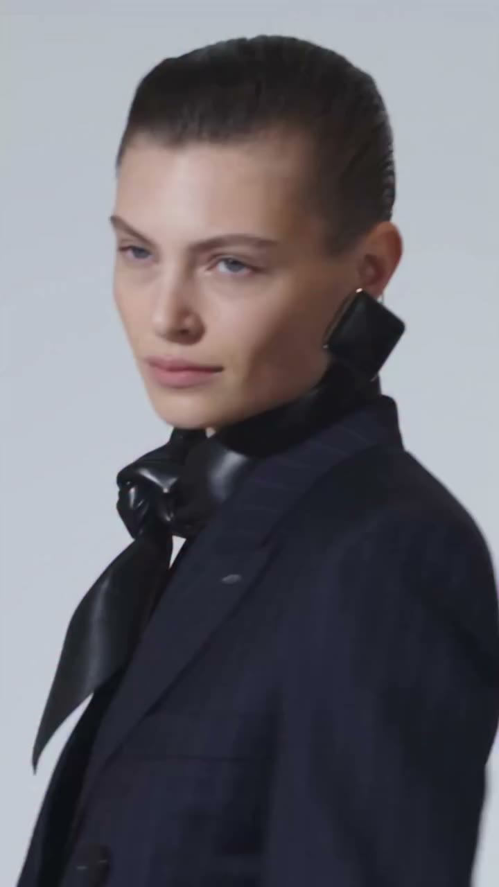 Bibi wears a double-breasted jacket with double-pleat trousers, a leather…