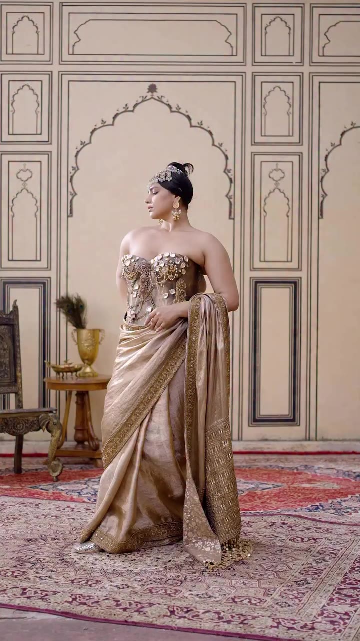 𝐏𝐨𝐥𝐤𝐢 The Puratan Tissue Brocade Metal Corset Saree Set pairs an…