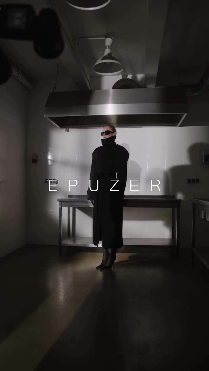 The long black wool coat, defined by a high collar, double-breasted fastening…