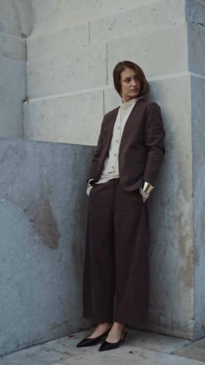 Soft tailoring against urban stone. A composed figure, caught between…