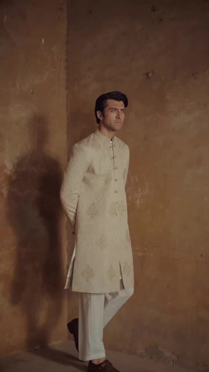 ZARRAR | A sophisticated beige sherwani featuring intricate tonal embroidery…