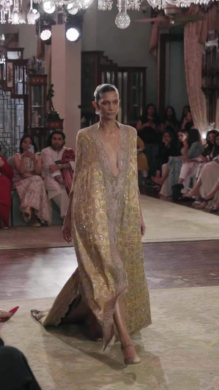A richly woven brocade cape adorned with intricate zardozi embroidery and…